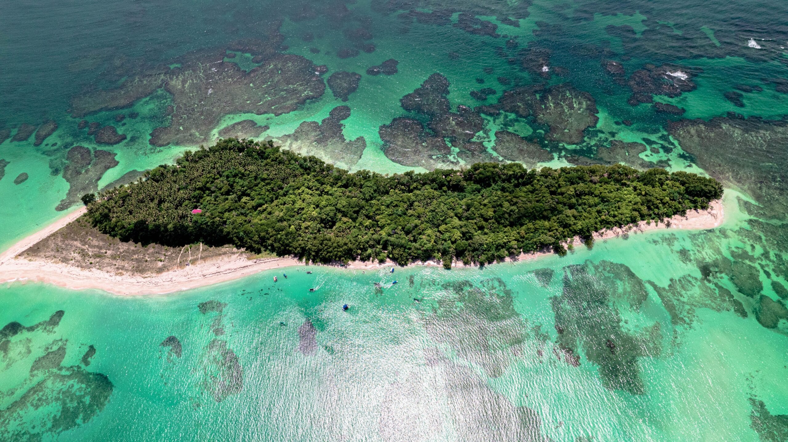 An aerial shot of a green island surrounded by tranquil ocean water in Bocas del Toro, Panama.